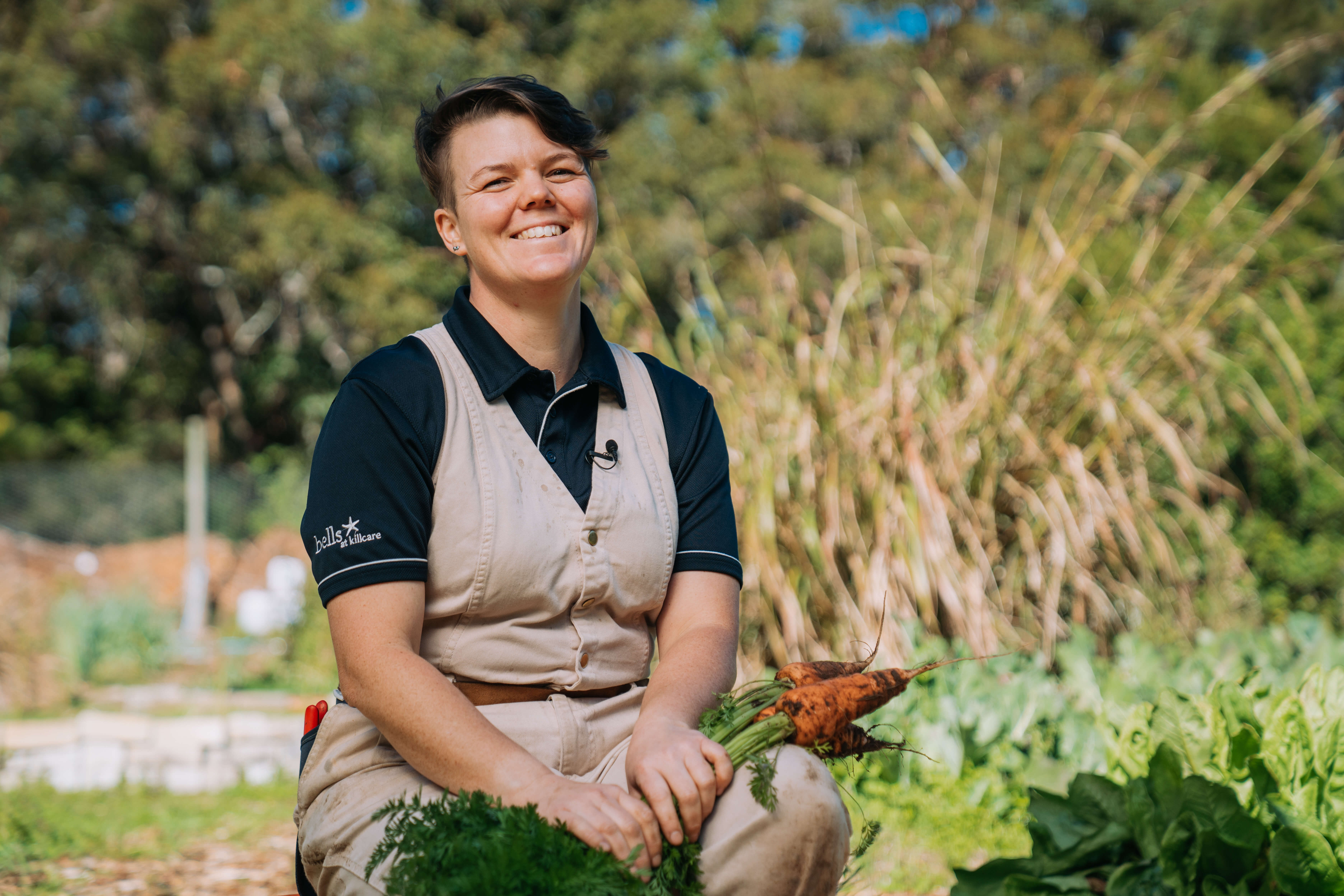A lady wearing an apron sitting in a garden