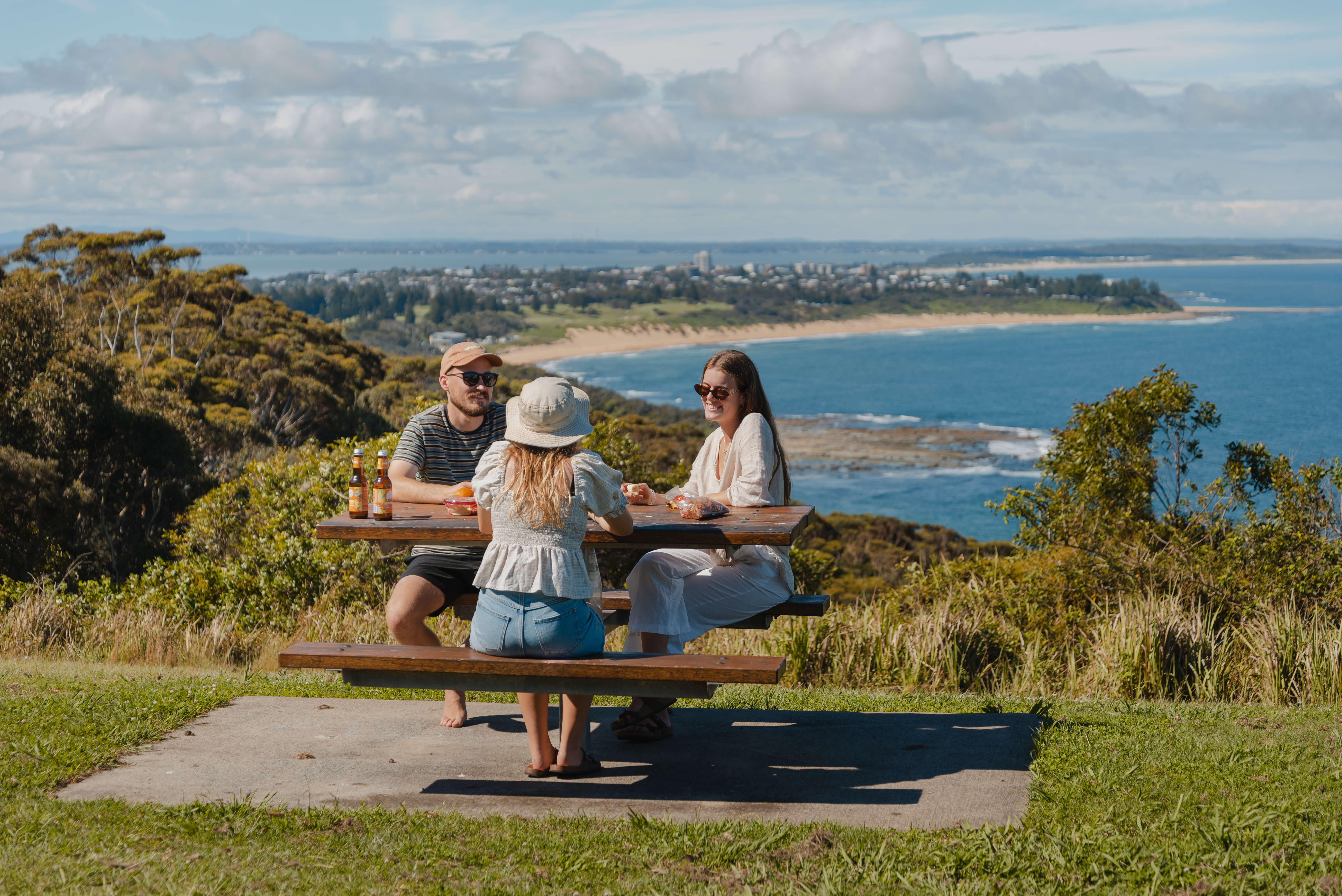 Three young adults sitting on a picnic table at the top of a lookout