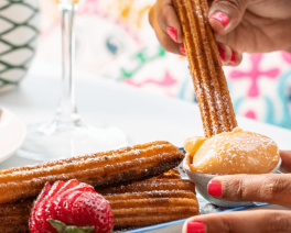Churros being dipped into caramel dipping sauce Don Pedros